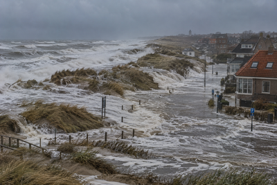 Stormvloed, zeer hoog water tot aan de duinvoet, krachtige branding, overslaand zeewater bij Nederlands kustdorp